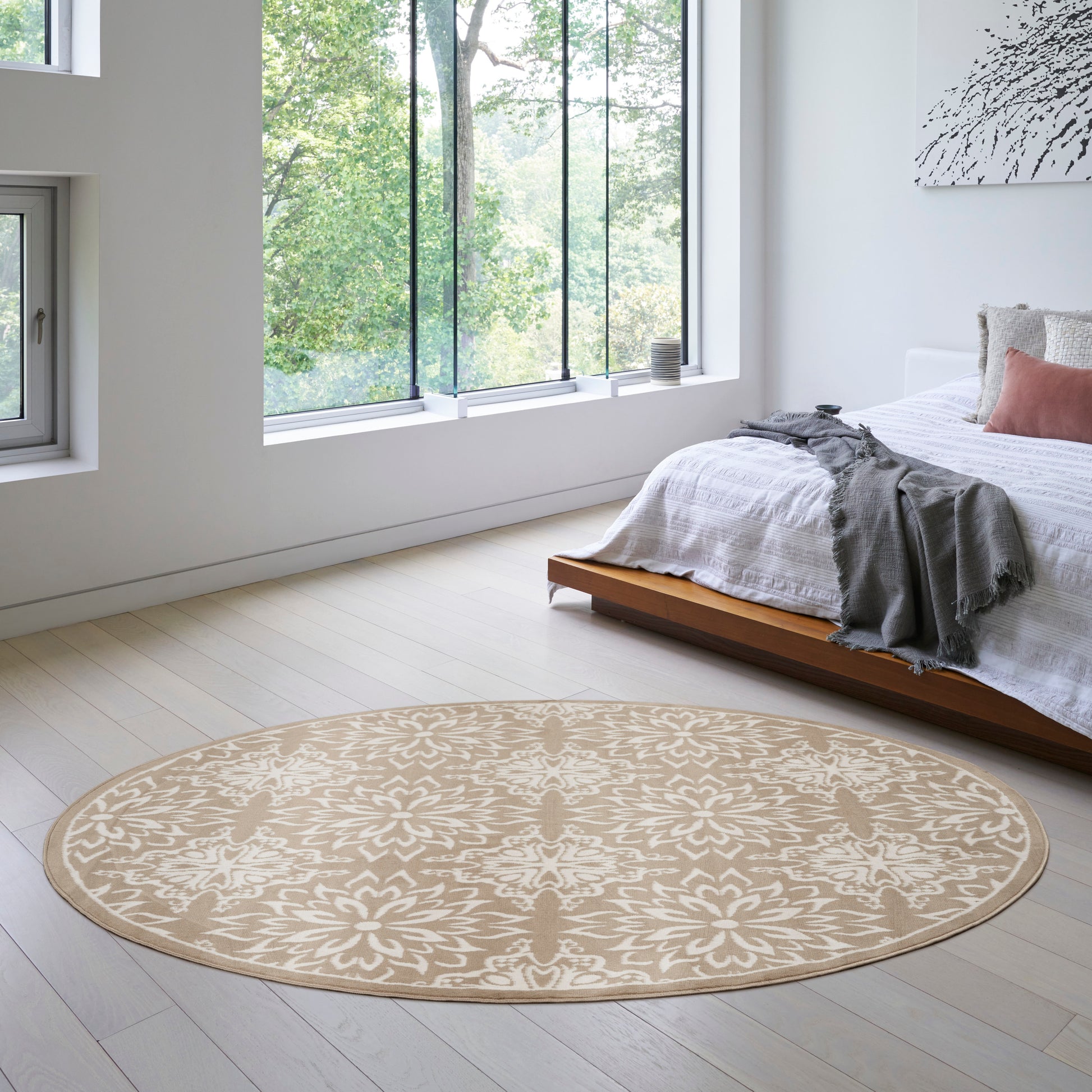 Round beige rug with ivory floral motif in a bright modern bedroom.