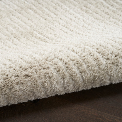 Cream shag rug with fluffy pile on dark hardwood floor, cozy living room floor mat.