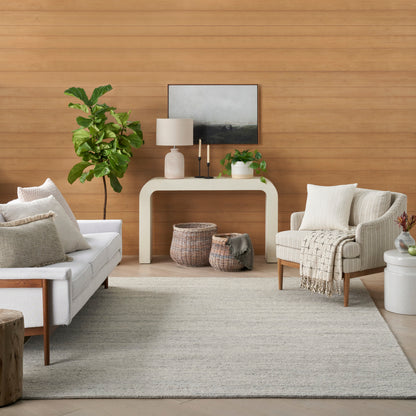 Living room with light gray sofa, beige armchair, fiddle-leaf fig, white console table, woven baskets, landscape art.
