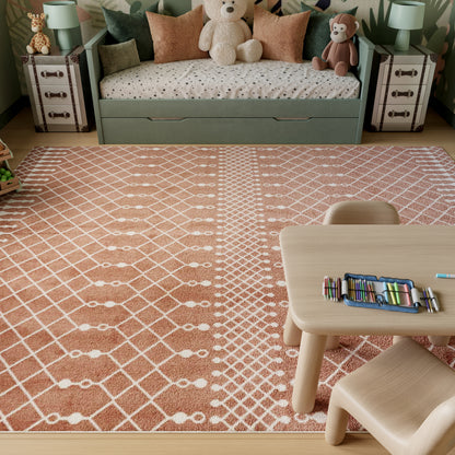 Soft pink kids' area rug with a white diamond lattice pattern; rectangular plush rug for playroom decor.