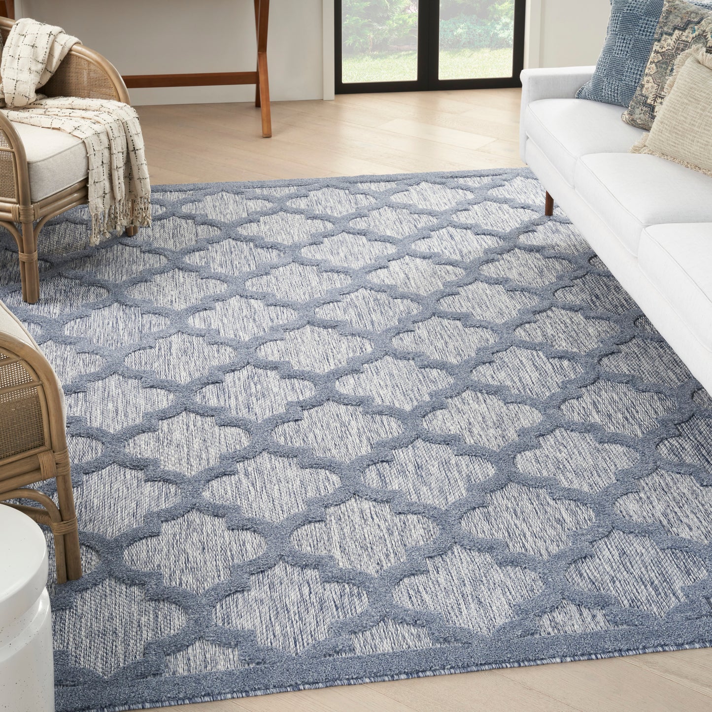 Blue-gray geometric trellis area rug with soft texture in a bright living room.