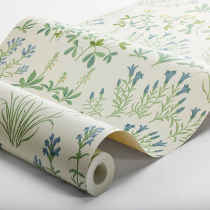 Cream wallpaper roll with green and blue leaf motifs; lavender-toned florals on a soft background.