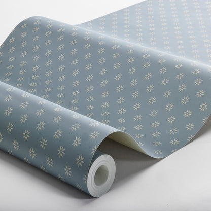 Slate wallpaper roll with tiny white motifs in a repeating pattern.