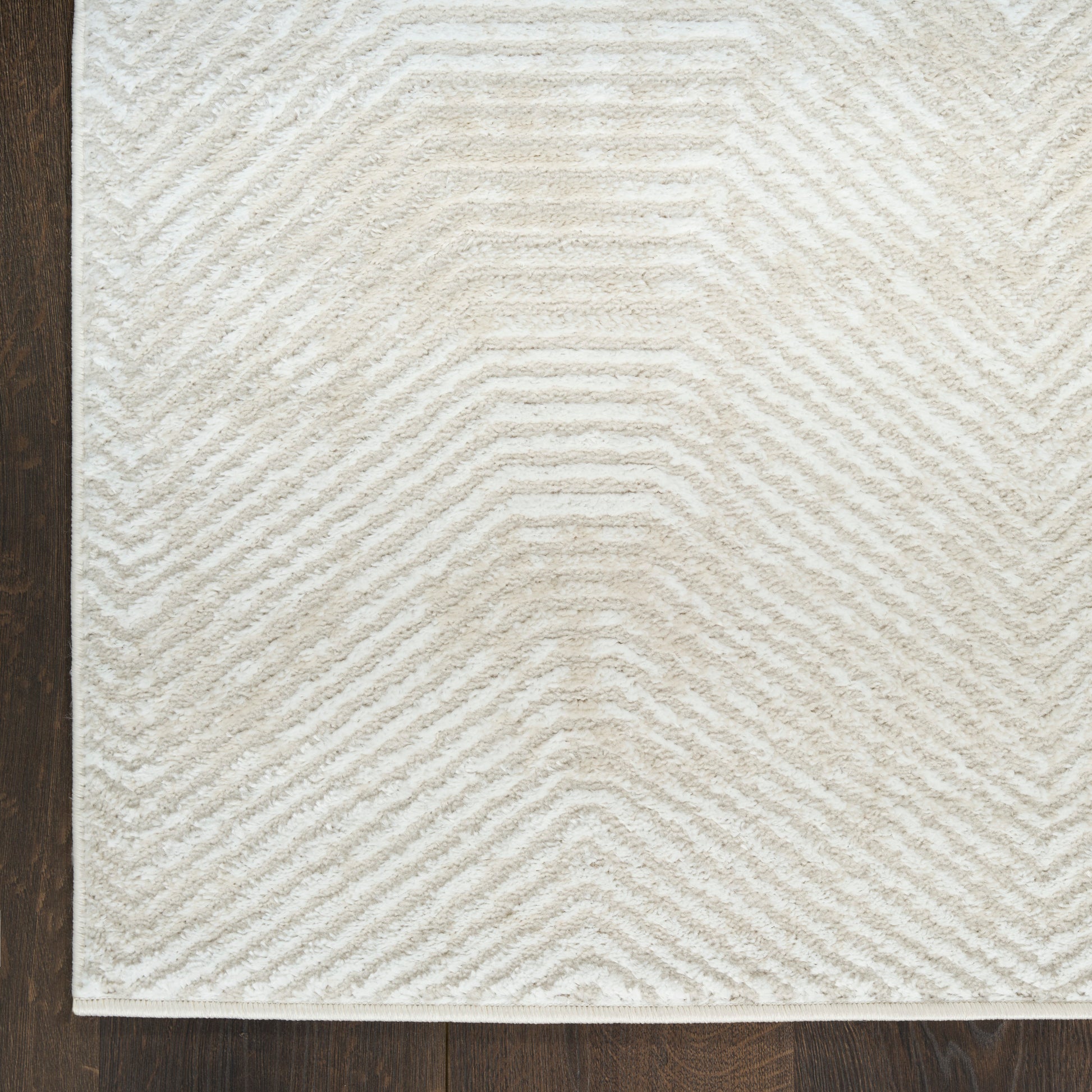Cream and beige chevron textured area rug with plush pile on dark wood floor