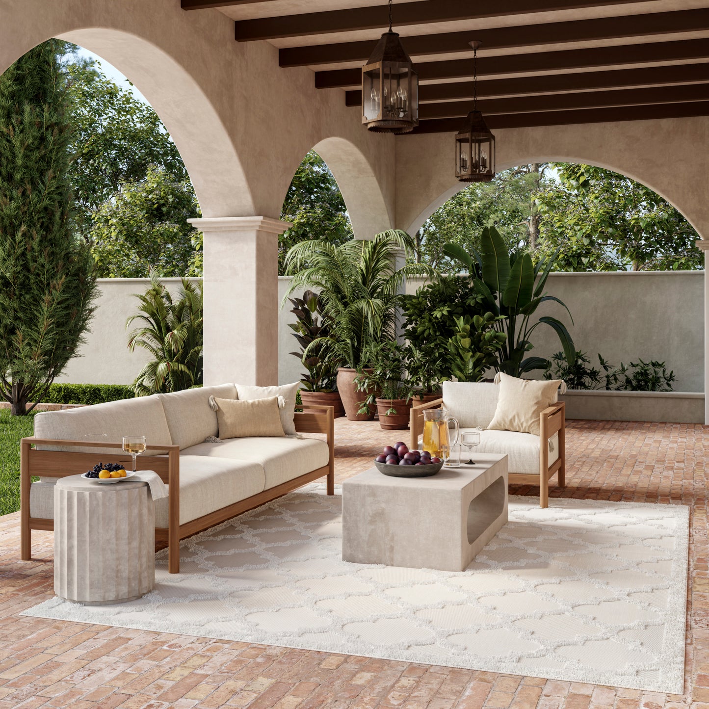 Outdoor lounge with cream cushioned wooden sofas, concrete cube coffee table, beige rug, archways, lanterns, tropical plants.