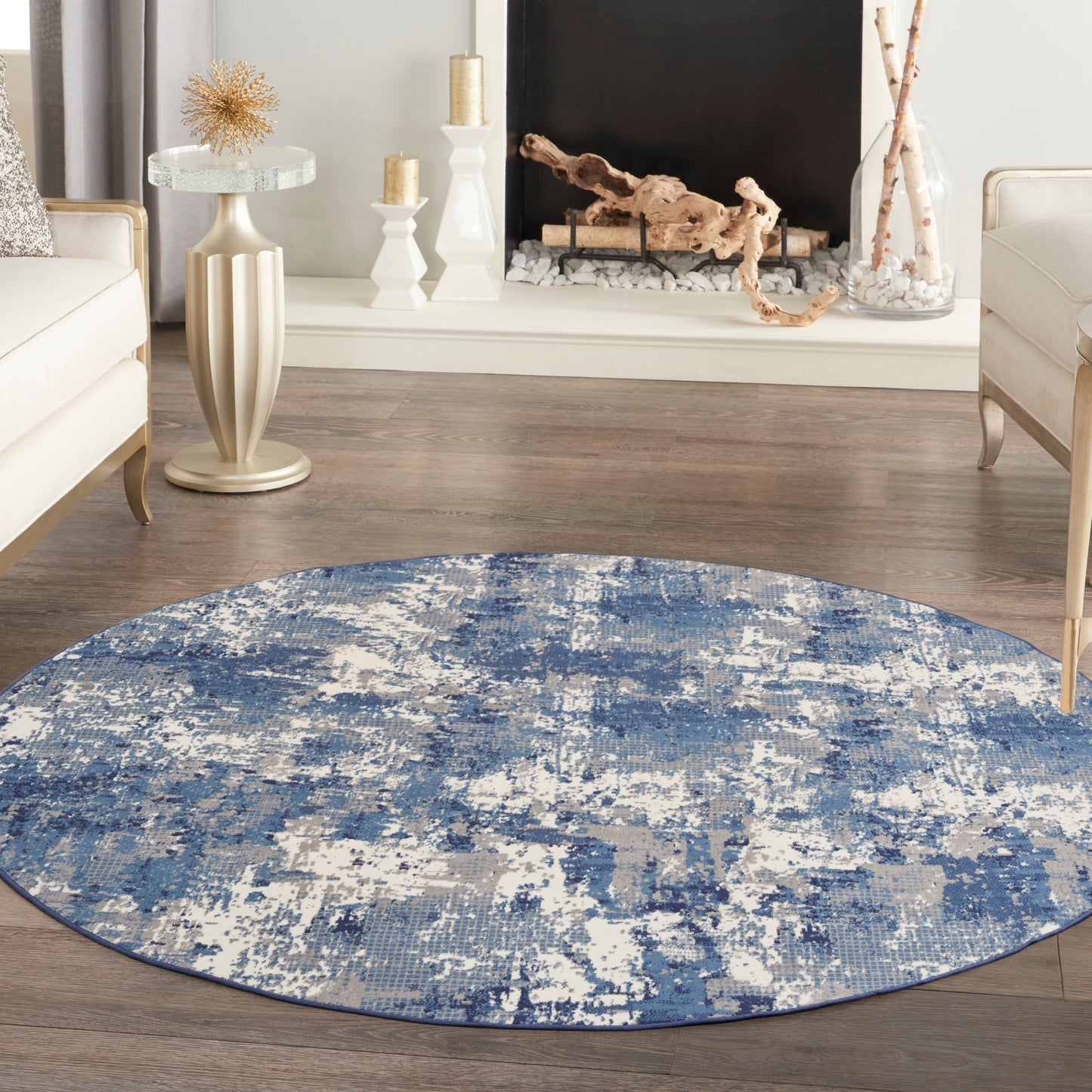 Round blue abstract circular rug on wood floor in a modern living room with cream furniture and a decorative fireplace.