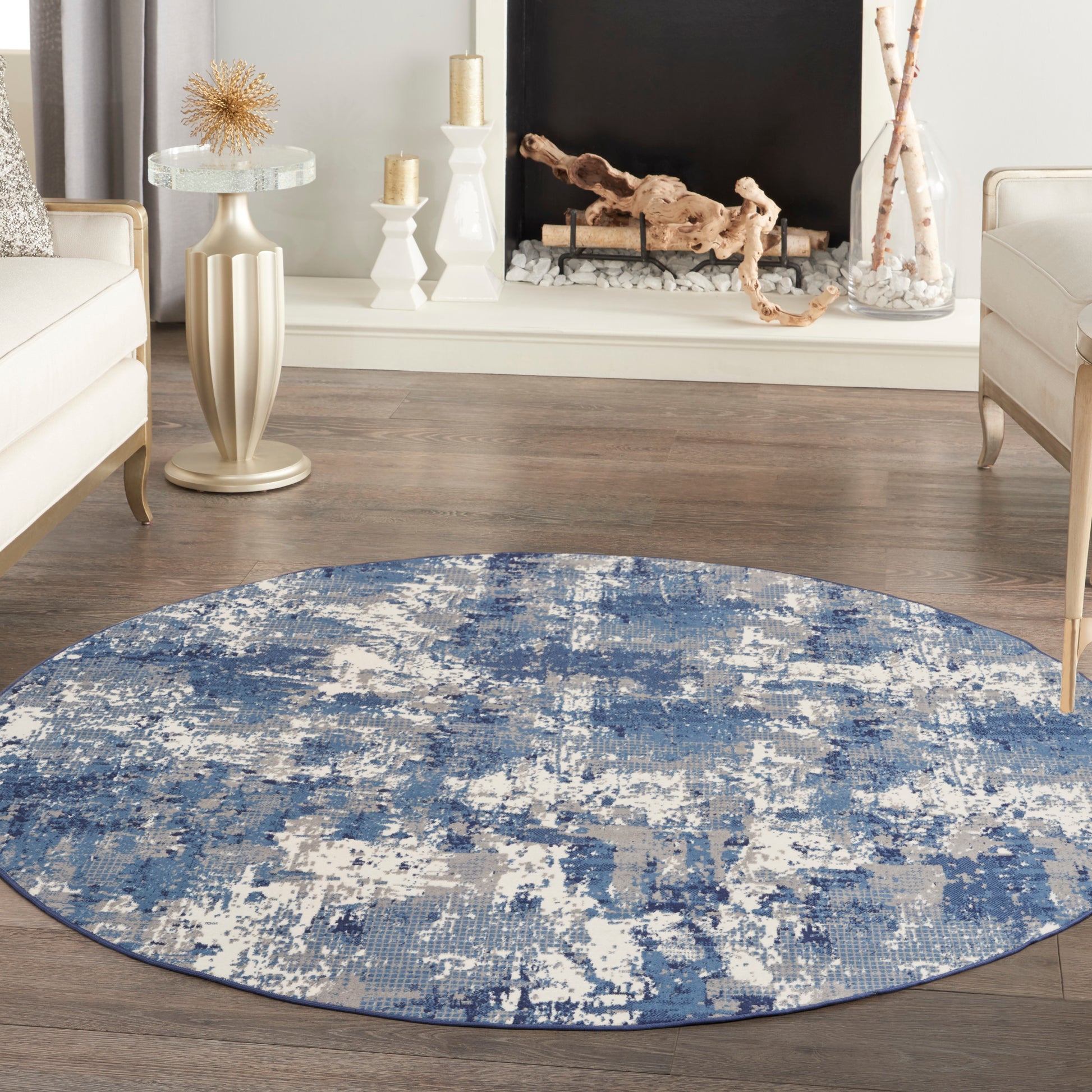 Round blue abstract circular rug on wood floor in a modern living room with cream furniture and a decorative fireplace.