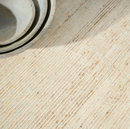Beige striped rug with pale gray-blue tones in a simple home setting.