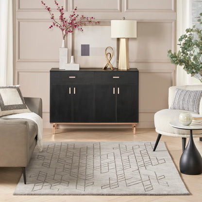 Black sideboard with gold legs and handles, topped with a lamp and decor, in a beige living room with a geometric rug.