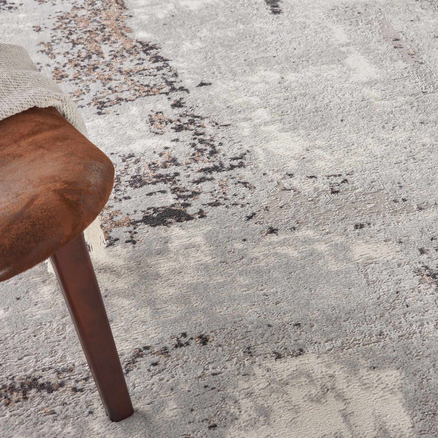 Dark wood chair leg with a beige knit sleeve, resting on a textured gray-beige rug.
