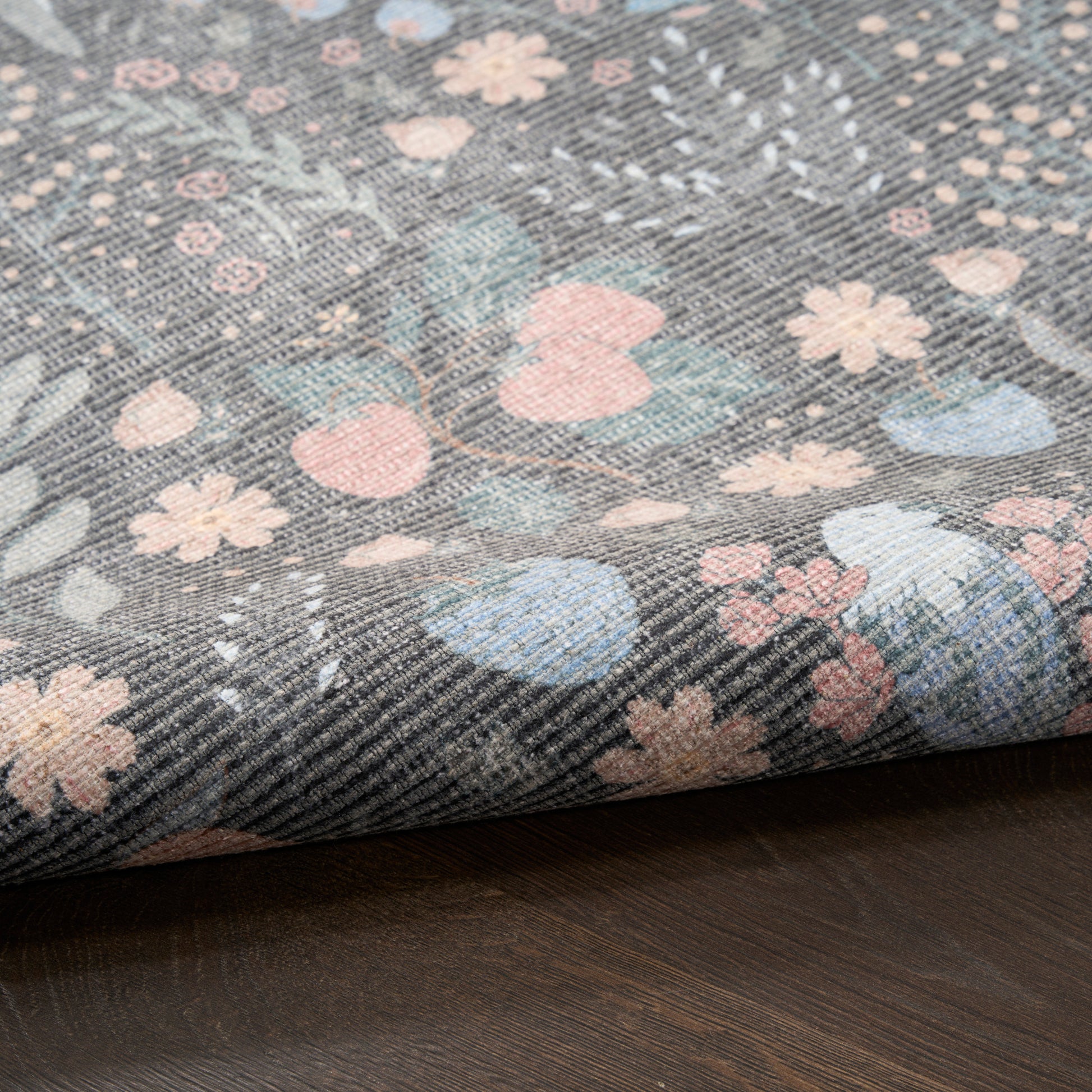 Denim-like fabric with pastel floral print in pink, blue and peach on gray twill, folded edge.