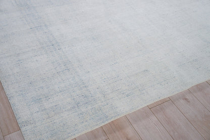 Light blue textured area rug with subtle marled pattern on light wood flooring.
