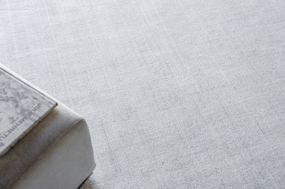 Rectangular light gray rug with a pale textured surface.