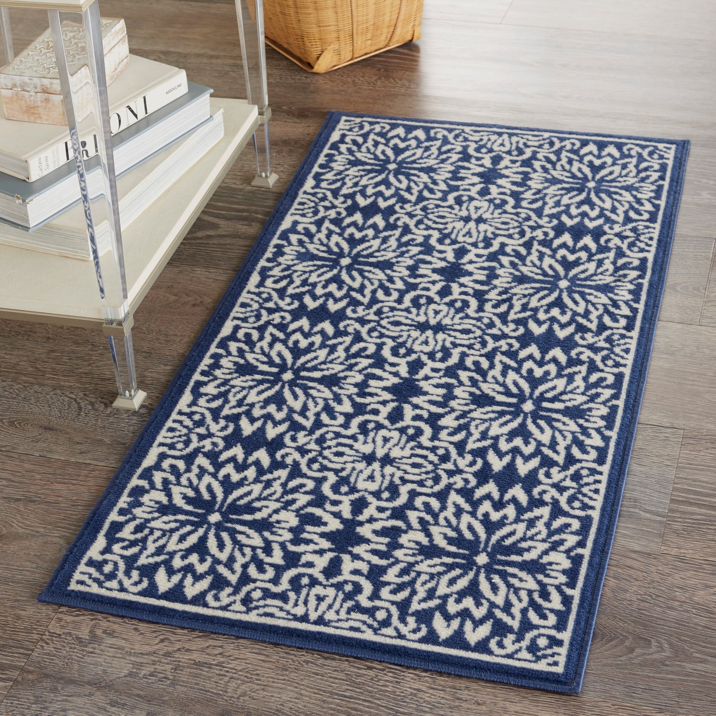 Rectangular navy rug with cream floral starburst motifs, 2' x 4', on dark wood floor