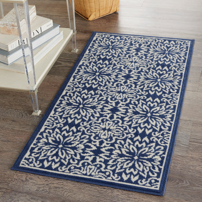 Rectangular navy rug with cream floral starburst motifs, 2' x 4', on dark wood floor