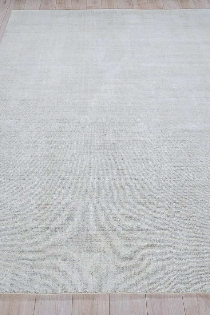 Rectangular light gray hand-loomed indoor rug with subtle texture on a wood floor.