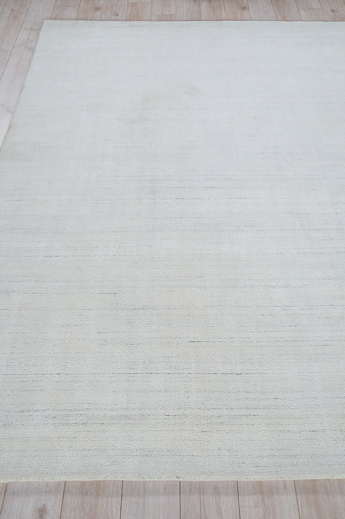 Rectangular light gray area rug, 6' x 9', with subtle linear texture on light wood floor.