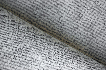 Close-up of grey textured woven rug with a speckled pattern, folded.