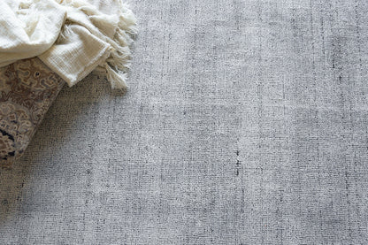 Cream fringed hand-loomed rug with a textured woven surface.