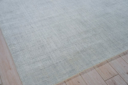 Rectangular light gray woven area rug with subtle texture on light wood flooring.