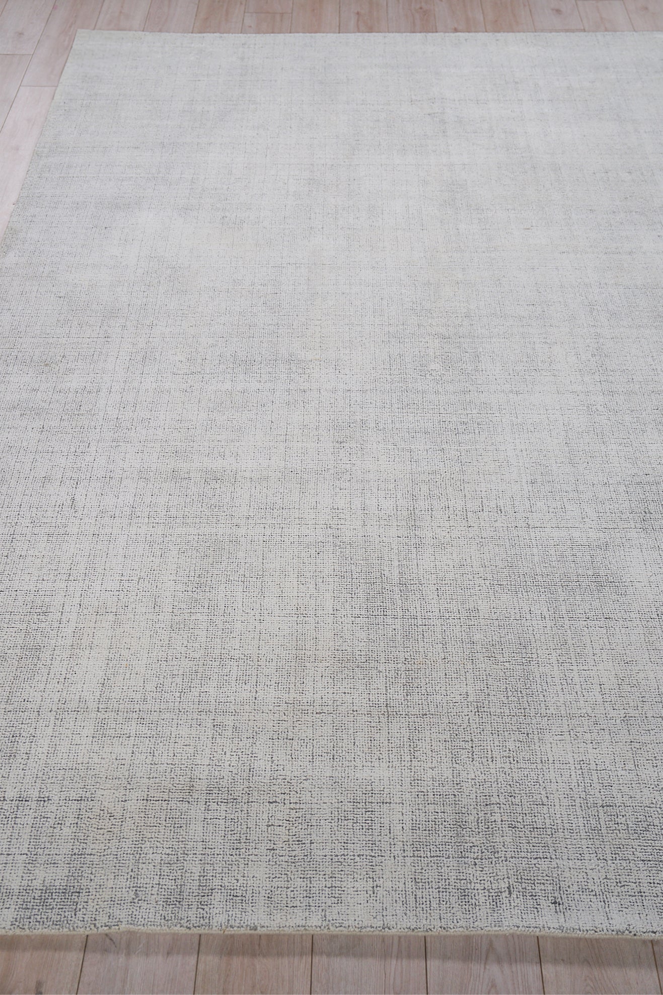 Rectangular light gray woven area rug with subtle texture on light wood floor.