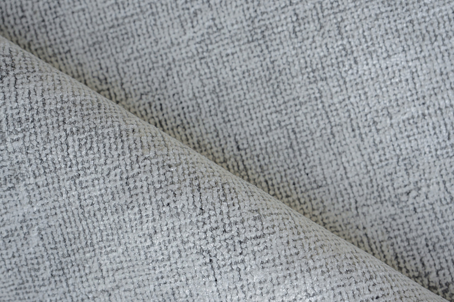 Close-up of a grey woven rug with a subtle textured weave and light speckle.