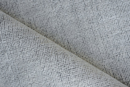 Close-up of light gray textured woven fabric with a speckled, grid-like pattern.