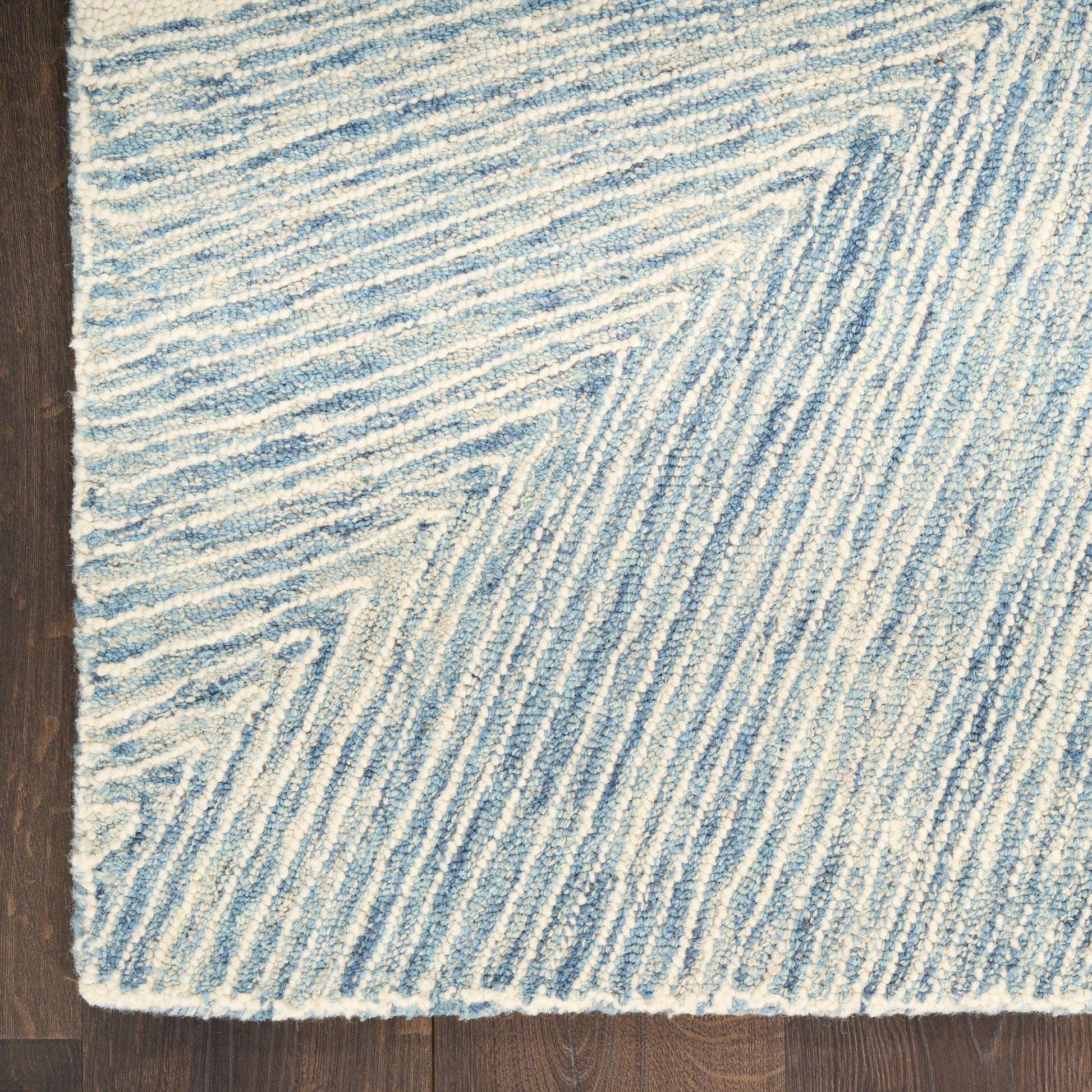 Blue & white textured woven runner with diagonal chevron stripes, plush pile on dark wood floor.