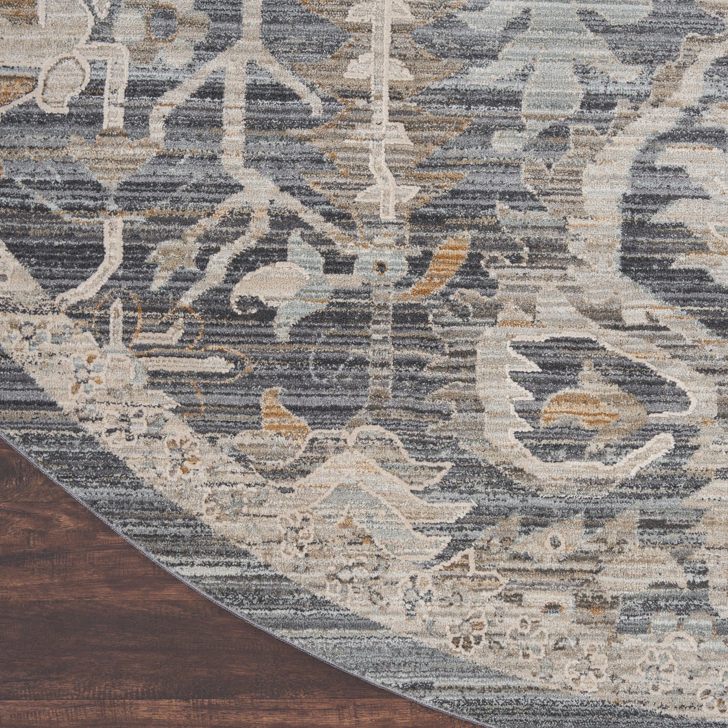 Blue-gray distressed oriental area rug with ivory floral motif, curved edge on dark wood floor.