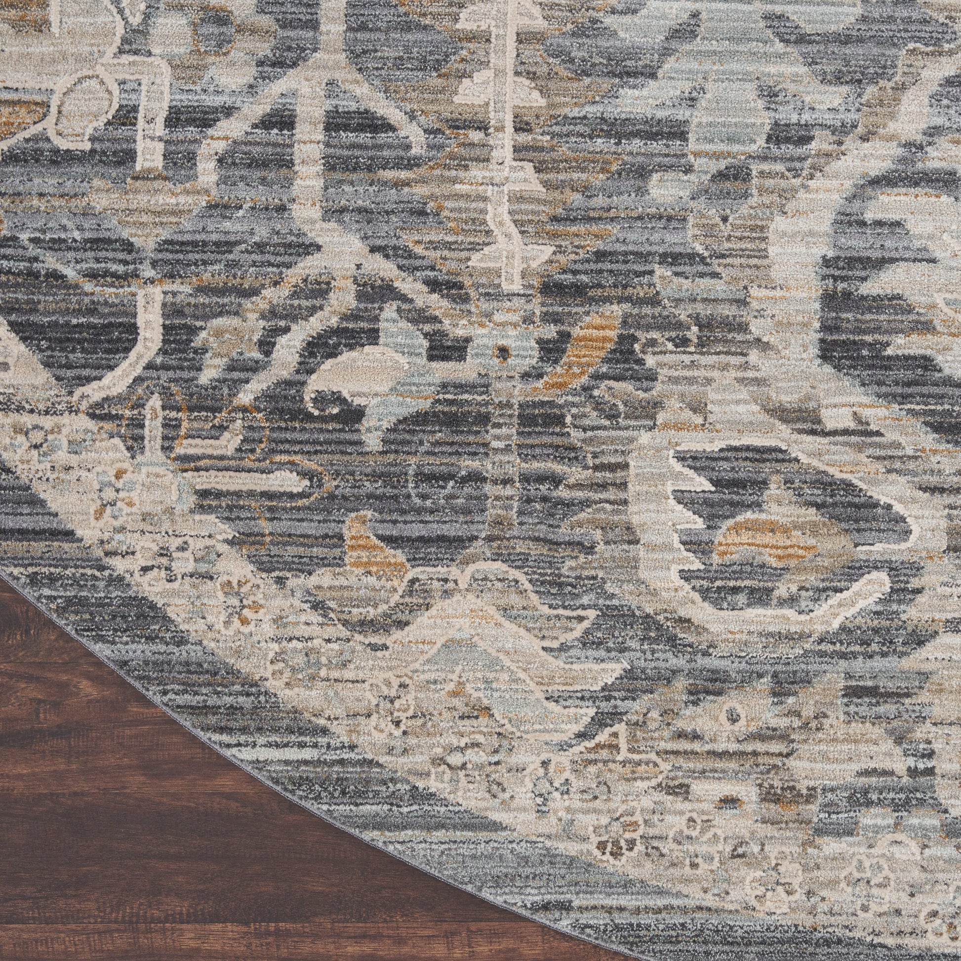 Blue-gray distressed oriental area rug with ivory floral motif, curved edge on dark wood floor.