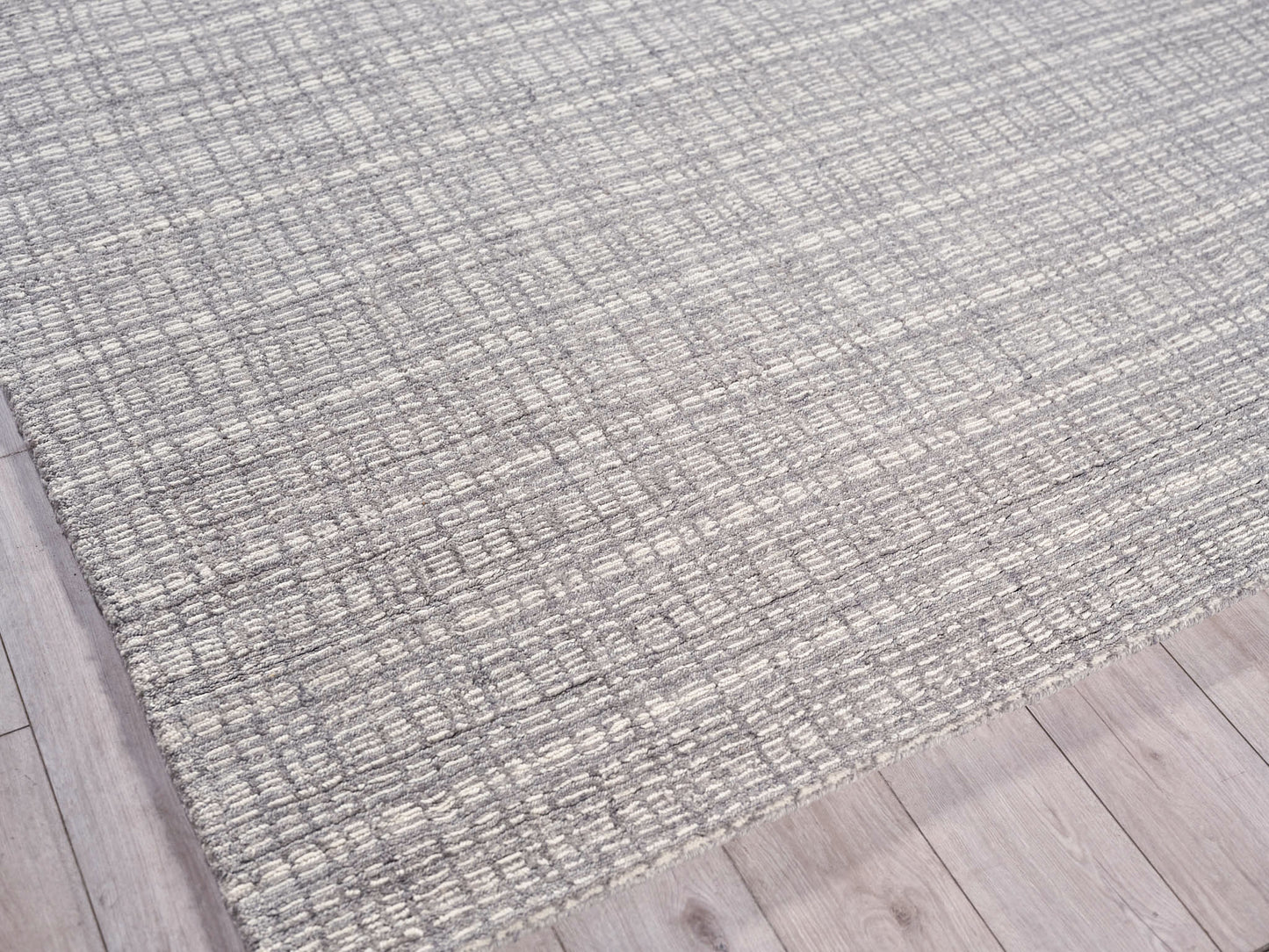 Grey textured woven area rug with a subtle loop pattern on light wood flooring; modern neutral style.