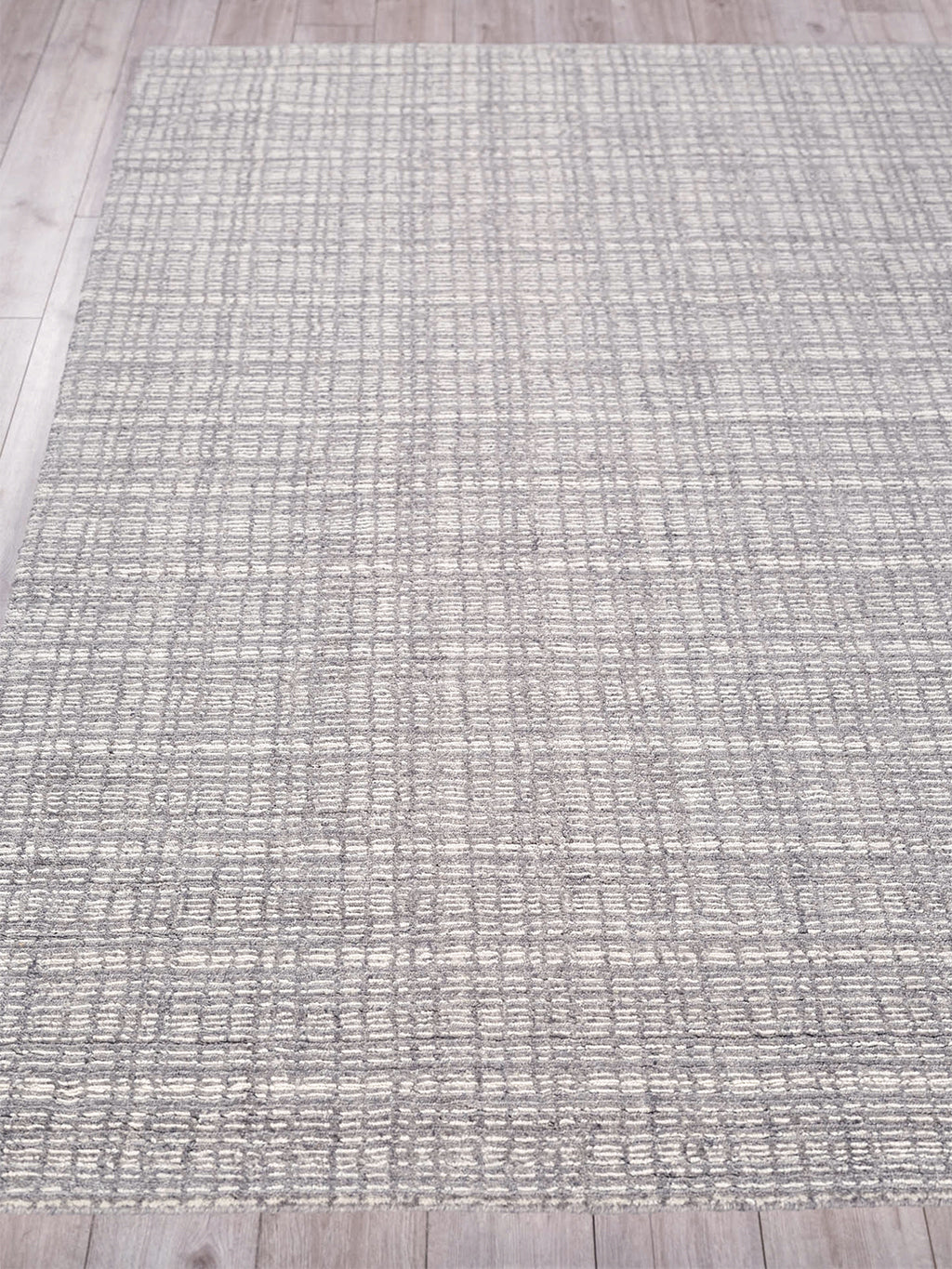 Rectangular gray hand loomed indoor area rug with a subtle grid pattern on a light wood floor.
