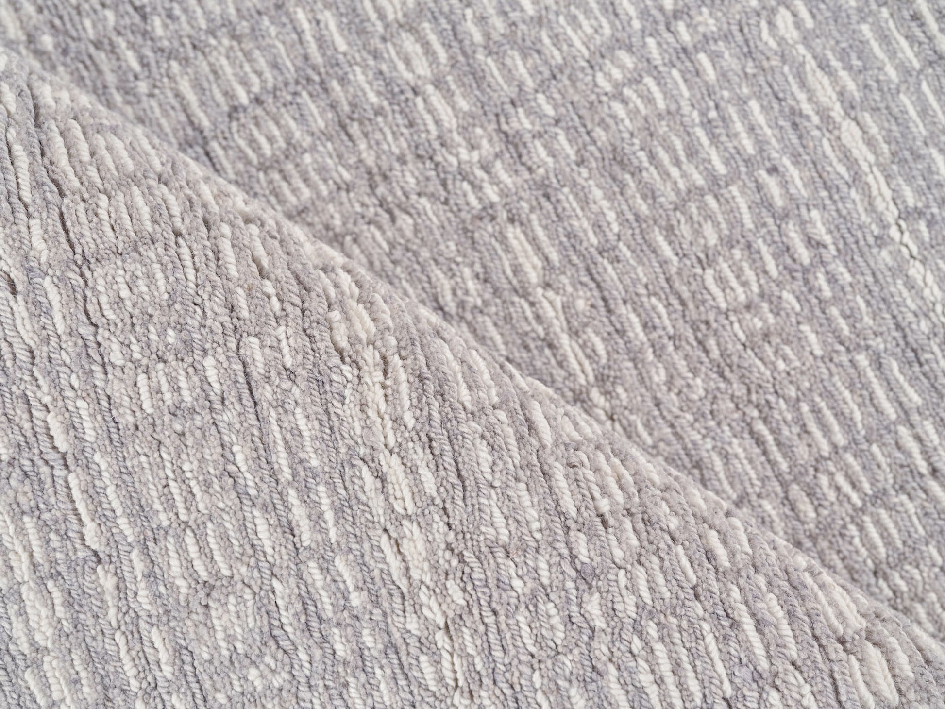 Gray boucle-textured rug with raised loop pattern and diagonal seam for cozy, modern home decor.