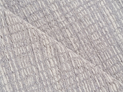 Gray boucle-textured rug with raised loop pattern and diagonal seam for cozy, modern home decor.