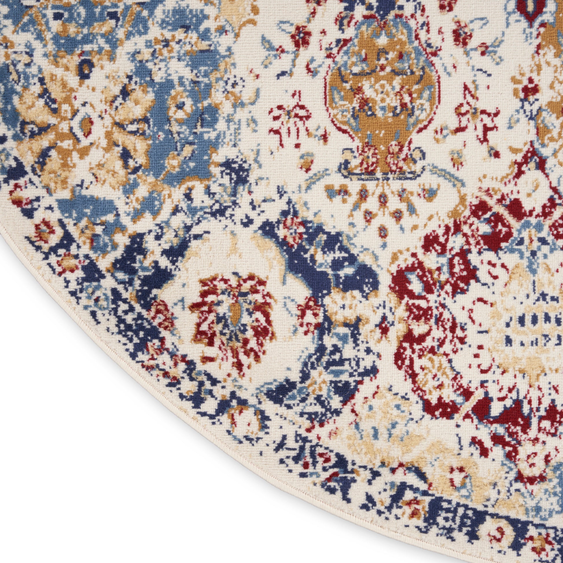 Close-up of a Persian-style rug with cream background, blue and gold floral medallions, red accents, and a folded corner.