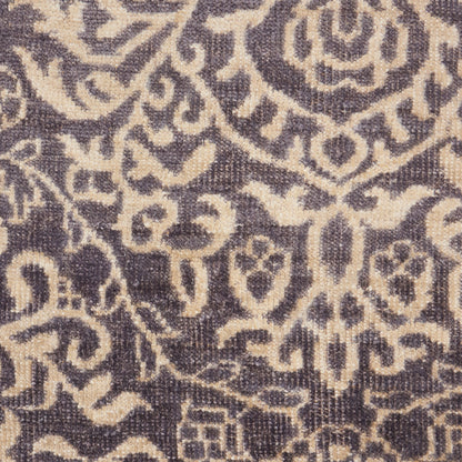 Close-up of beige damask floral pattern on purple woven rug; ornate scrolls and medallion motifs.