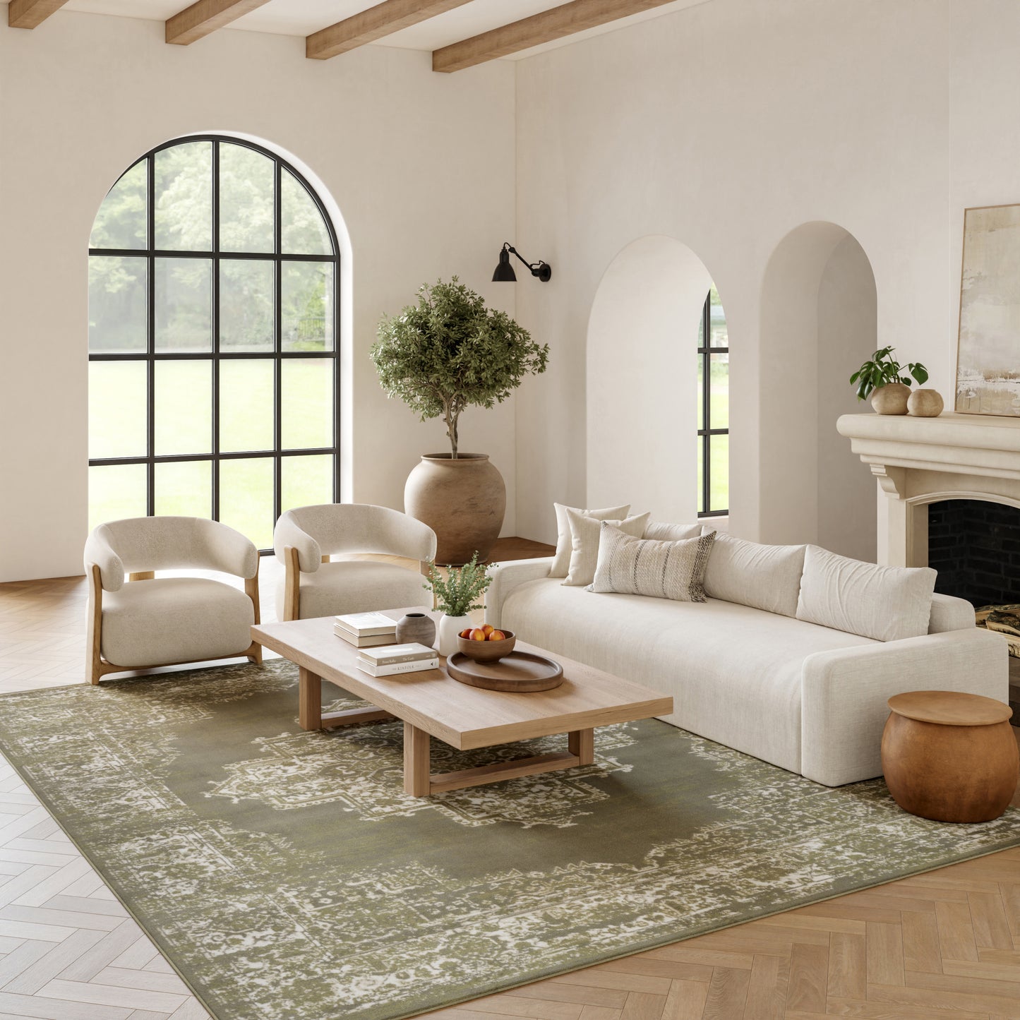 Neutral living room with arched window, beige sofa, cream chairs, wooden coffee table, green rug, potted plant, fireplace