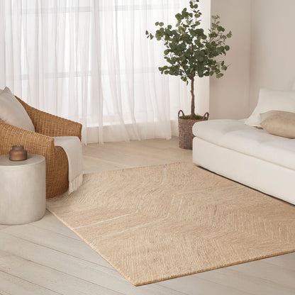 Neutral beige jute rug on light wood floors in a bright living room with white sofa, wicker chair, and potted plant.
