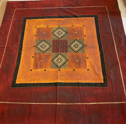 Colorful square wall hanging featuring geometric patterns in burnt orange, brown, and black. Artistic ethnic design, soft fabric.