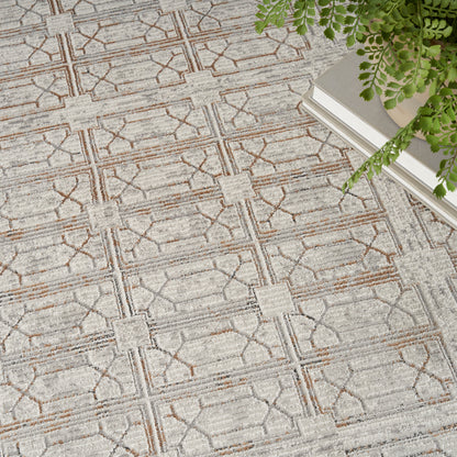 Beige-gray geometric area rug with square motifs and brown lines; fern and books sit at the edge.