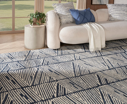 Cream sofa with blue cushions and beige throw; navy geometric area rug with diagonal line triangles in a modern living room.