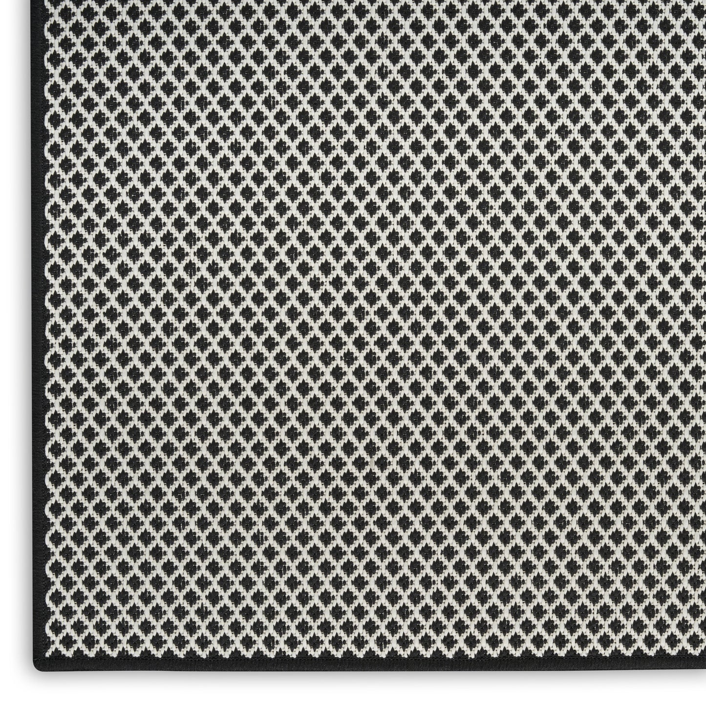 Close-up of black and white diamond lattice woven fabric with a textured surface and dark edge binding.