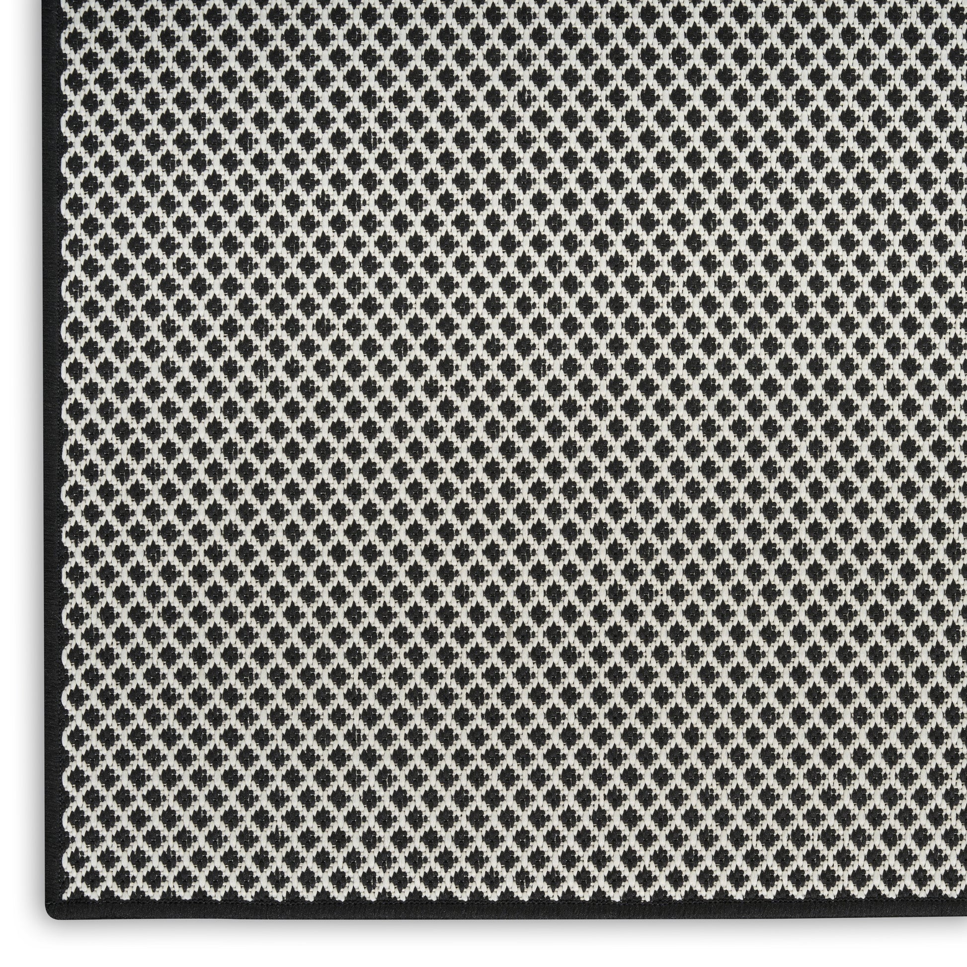 Close-up of black and white diamond lattice woven fabric with a textured surface and dark edge binding.