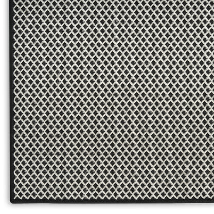 Close-up of black and white diamond lattice woven fabric with a textured surface and dark edge binding.