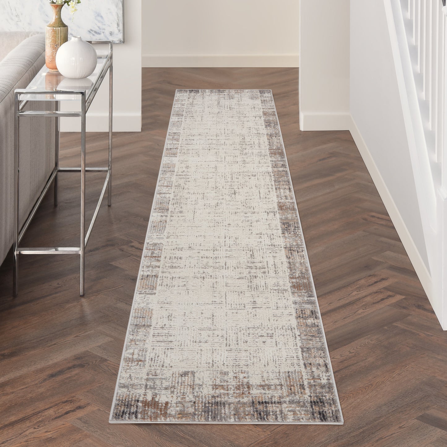 Neutral distressed runner rug in beige and taupe on herringbone hallway floor with a console table.