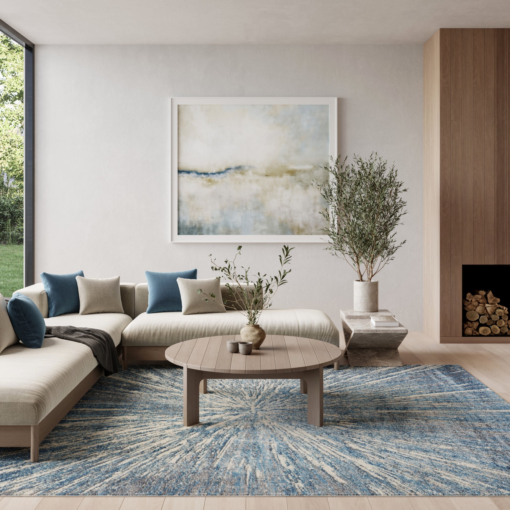 Modern neutral living room with beige sectional, blue cushions, round wood coffee table, blue abstract rug, tall plant.
