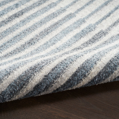 Close-up of blue and white striped runner rug with soft, plush texture, edge curling over a wooden floor.