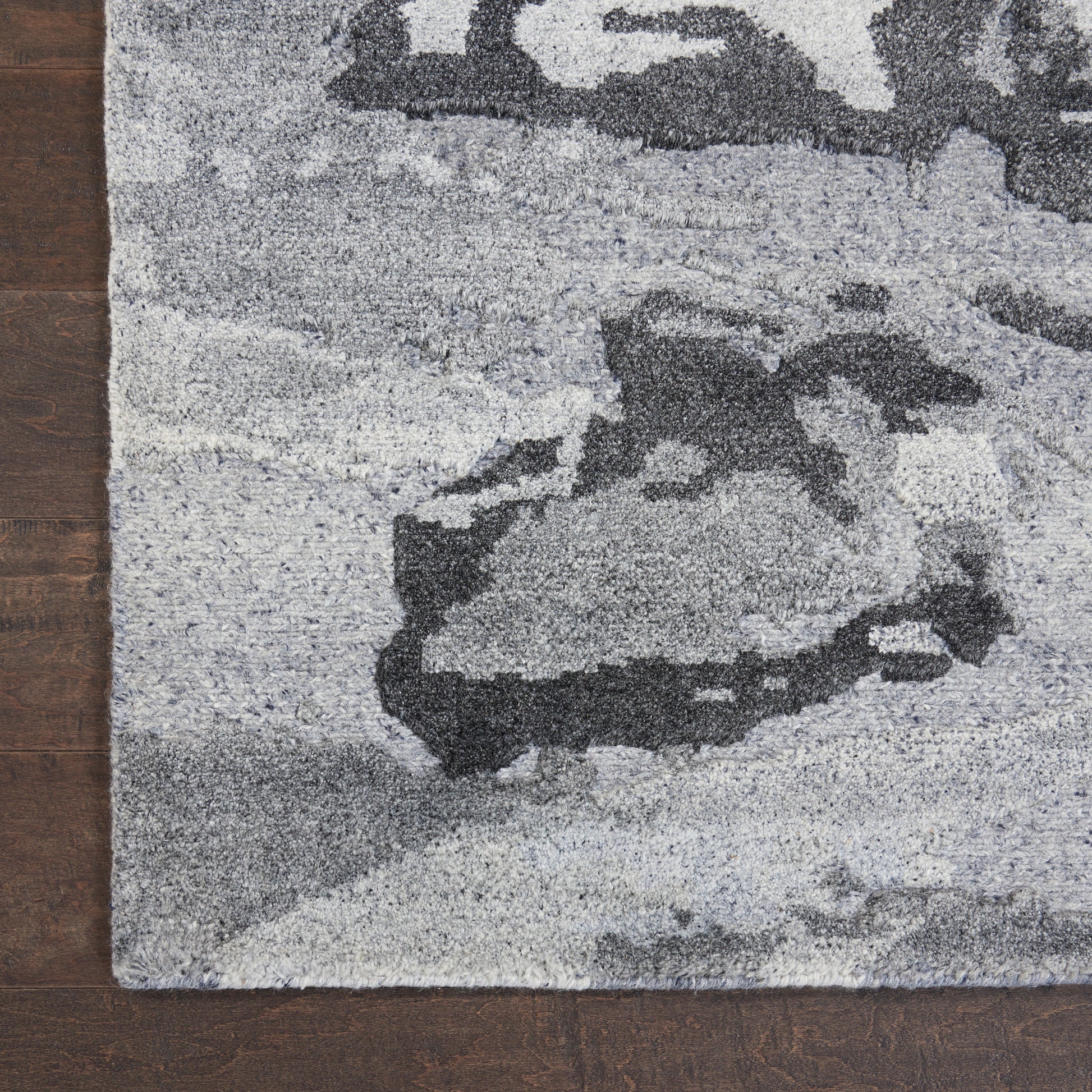 Gray abstract-pattern rug with rocky shapes in charcoal and light gray on wooden floor