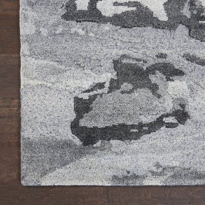 Gray abstract-pattern rug with rocky shapes in charcoal and light gray on wooden floor