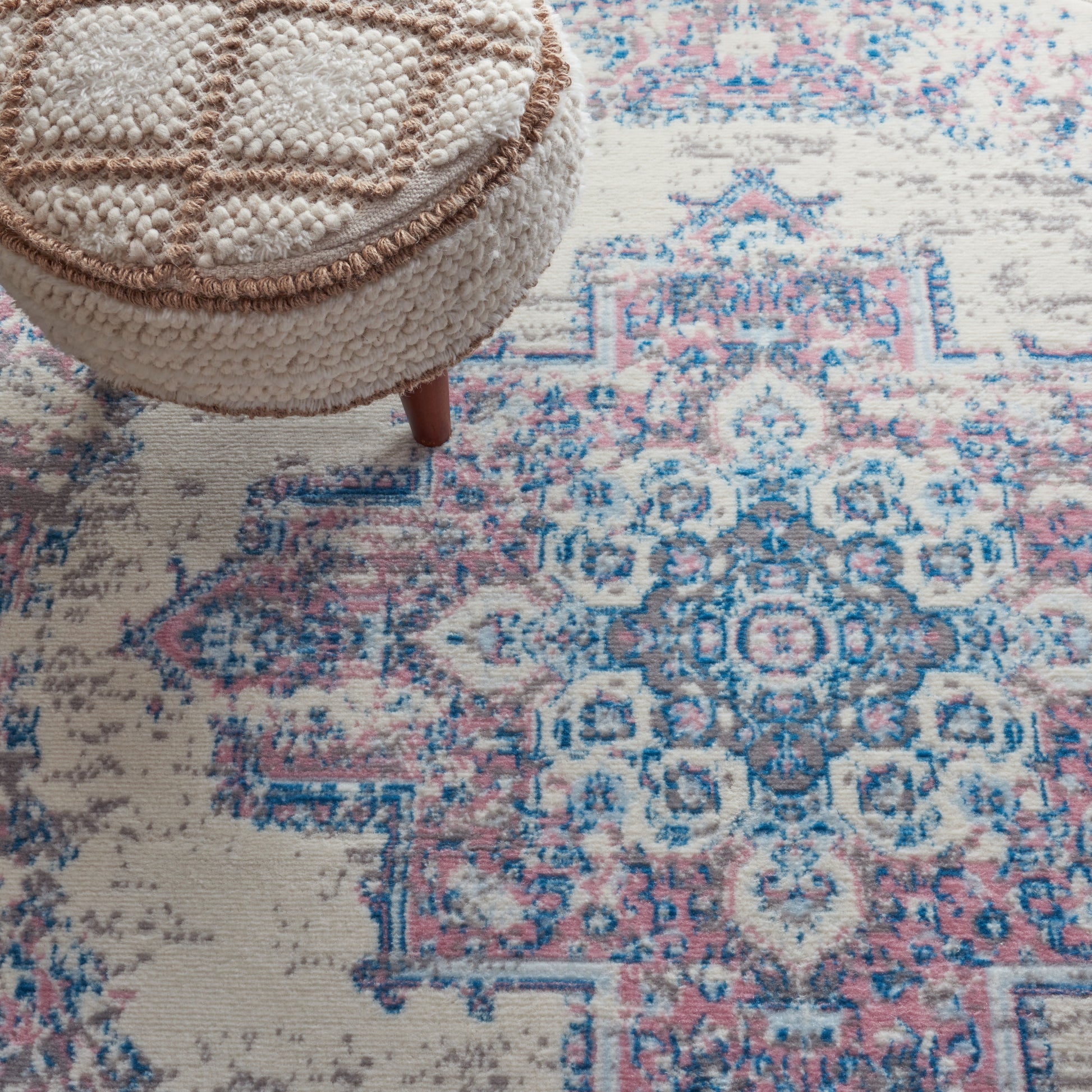 Beige boucle round rug with brown trim in a pink and blue Persian-style design.